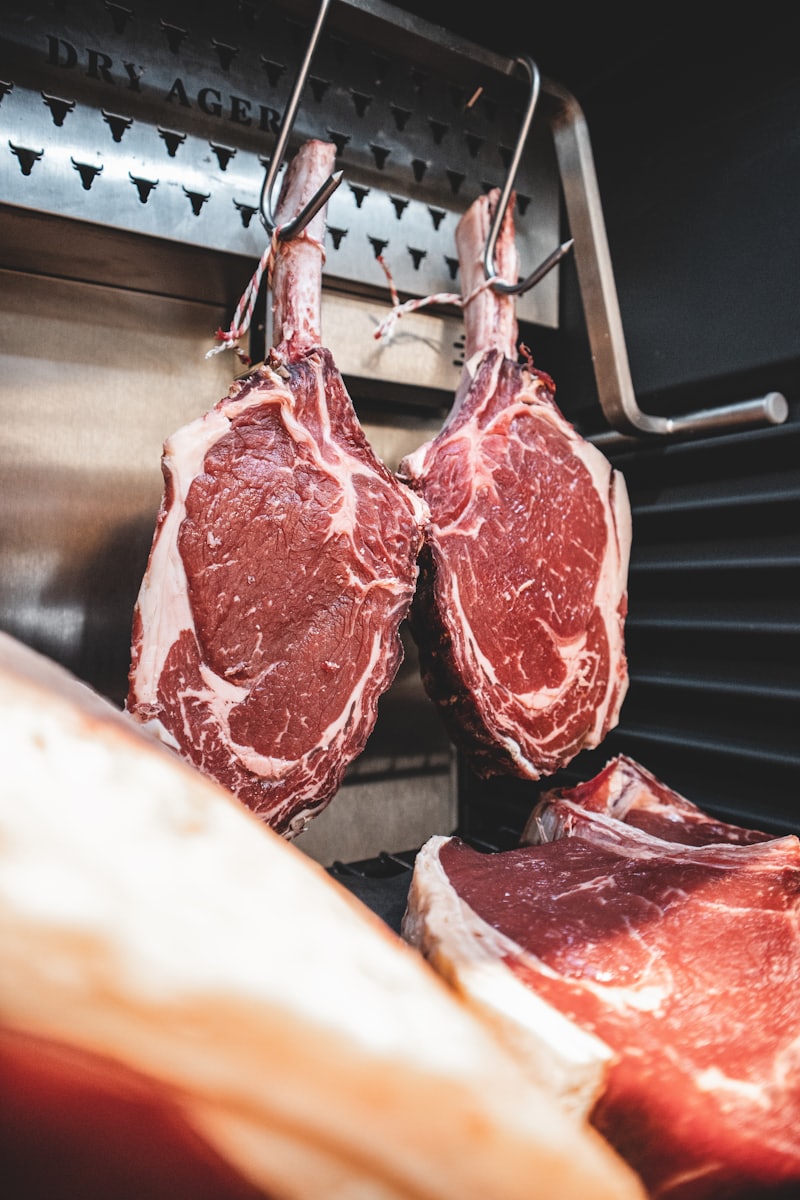Steaks hängen in einem beleuchteten Dry-Aging-Schrank